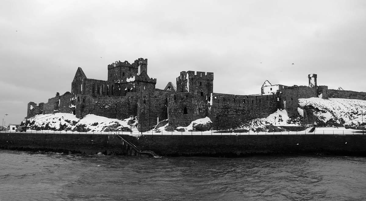 castle grayscale photo of concrete castle beside sea architecture
