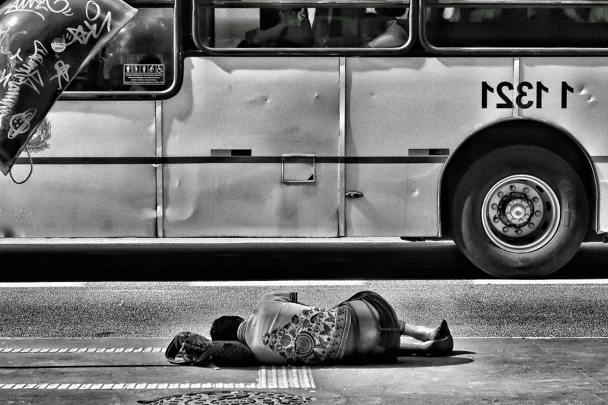 black-and-white grayscale photography of person laying on ground near bus shoe
