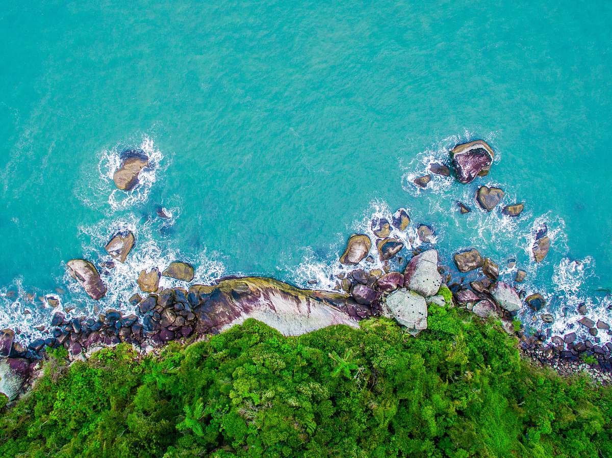 nature green and gray cliff near body of water in high angle photography water