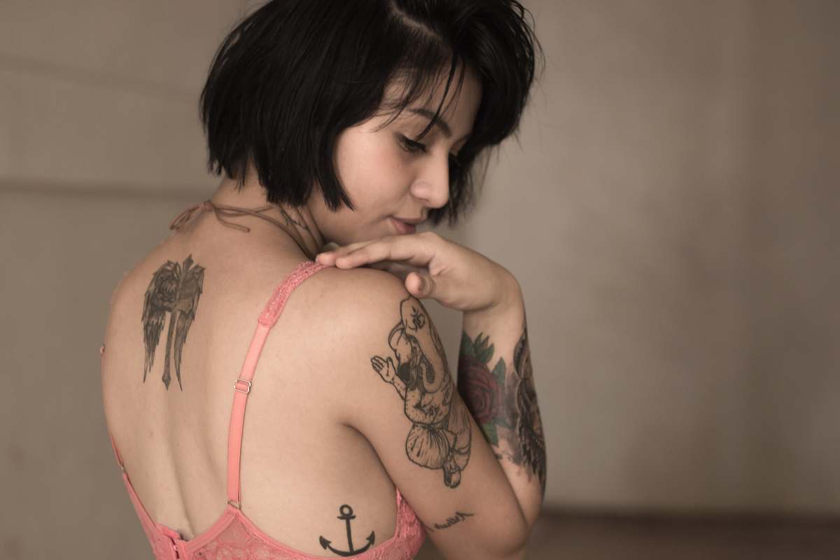 This striking image features a confident woman standing gracefully in a pink bra and matching lingerie set, her body adorned with intricate tattoos. The juxtaposition of the delicate lingerie and bold body art creates a unique and empowering visual. Perfect for fashion, beauty, and body positivity campaigns, this image can be used in advertisements, editorial pieces, or social media content aiming to celebrate individuality and self-expression.