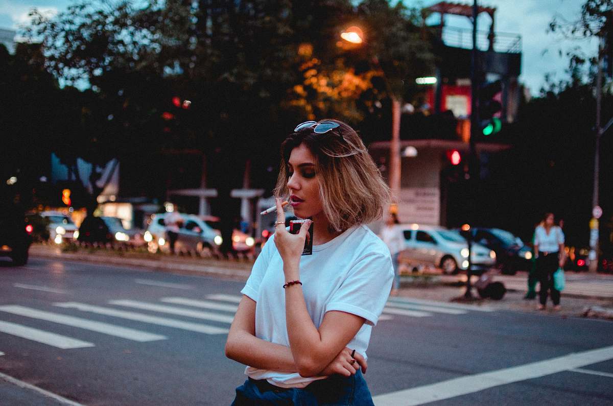 tarmac woman smoking single cigarette near vehicles and people asphalt
