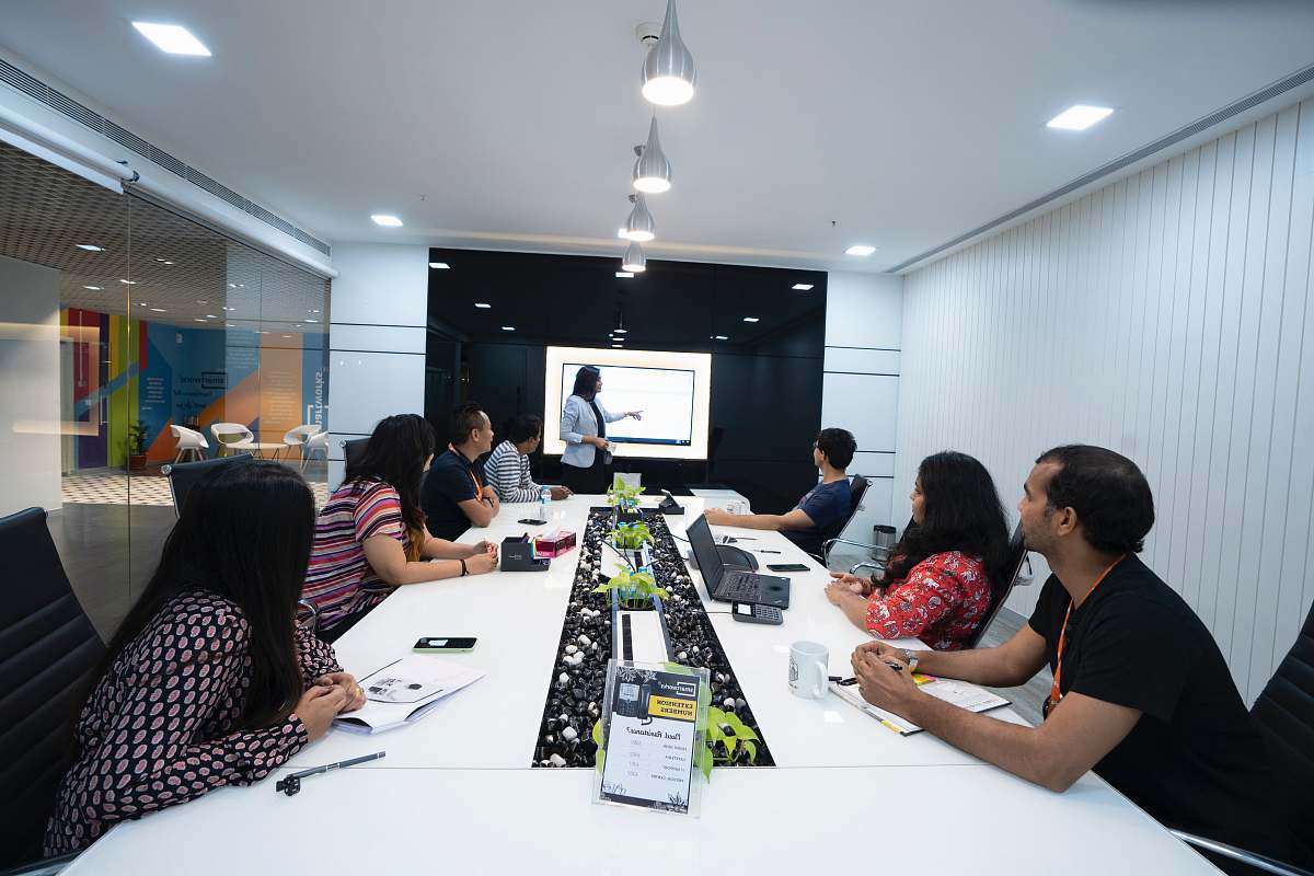  people sitting at the table looking to another person standing in front of them 