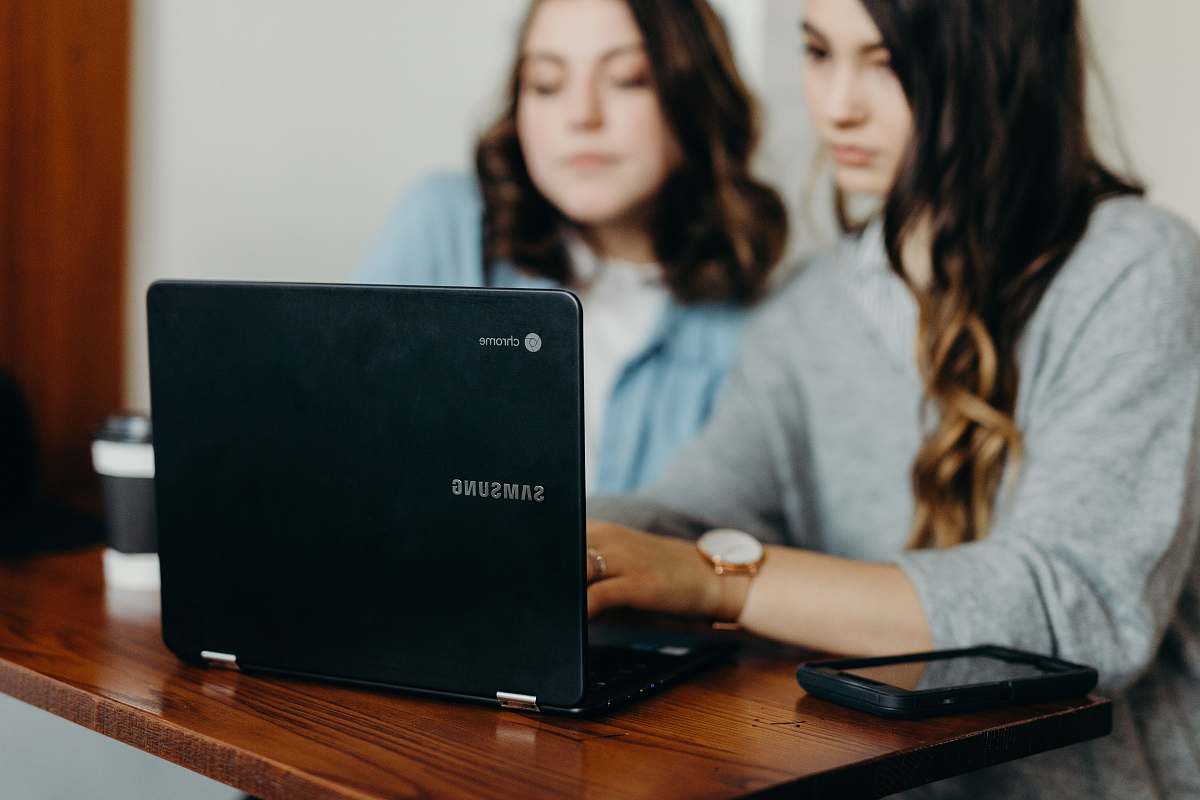 Explore the dynamic scene of two women engaging in productive collaboration, seated at a table with a laptop. This image captures the essence of teamwork and modern technology, perfect for illustrating themes of partnership, innovation, and remote work. Ideal for use in articles, presentations, or marketing materials focused on women's empowerment, technology in the workplace, or digital collaboration.