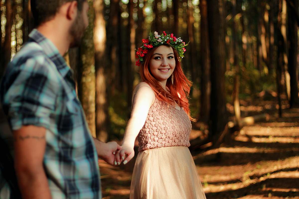 human couple holding hands while standing near tree barks person