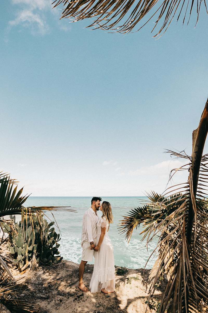 clothing man and woman standing near coconut tree plant
