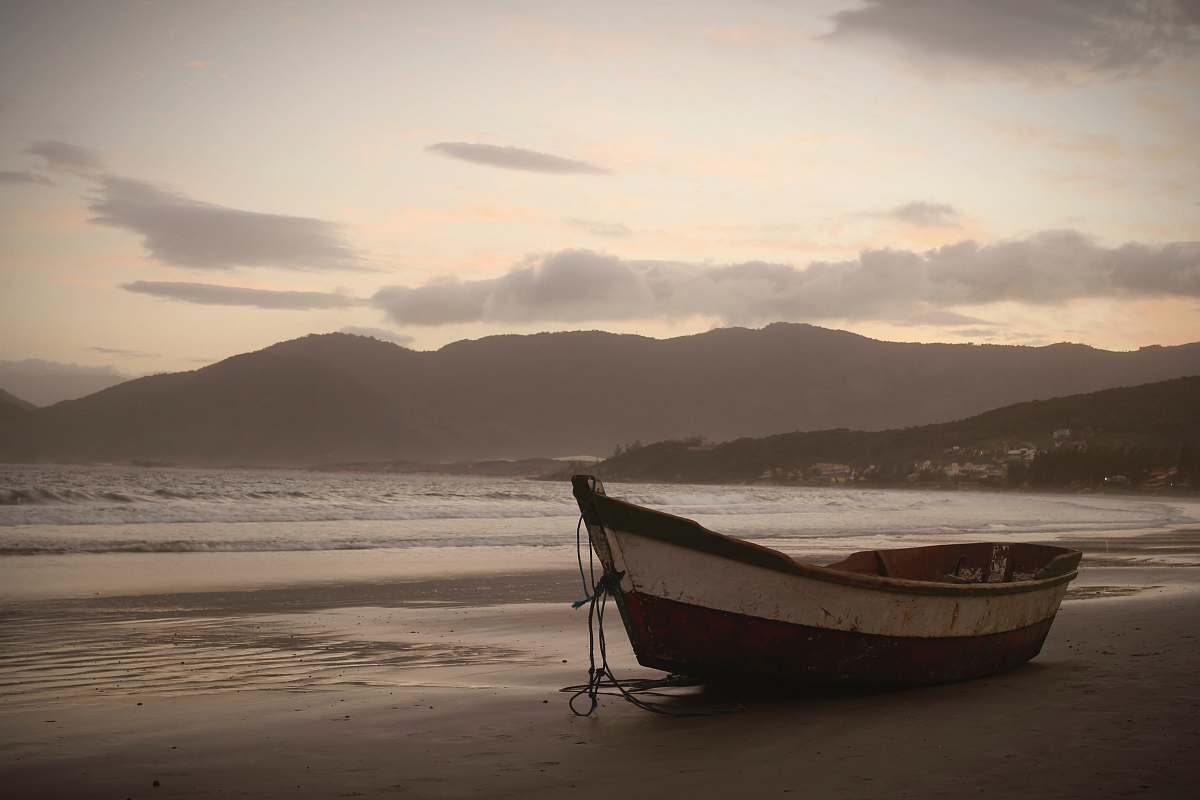 rowboat brown on seashore near body of water under cloudy sky at daytime transportation