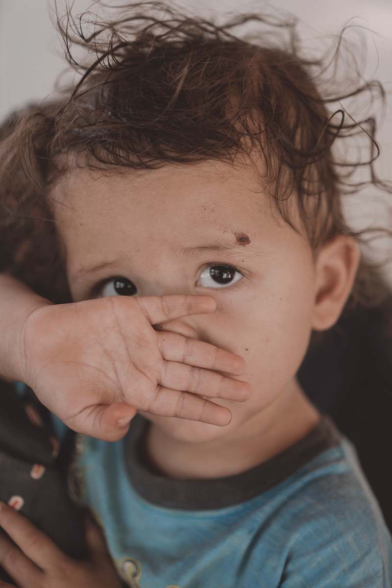 human toddler covering their nose and mouth with their hand person