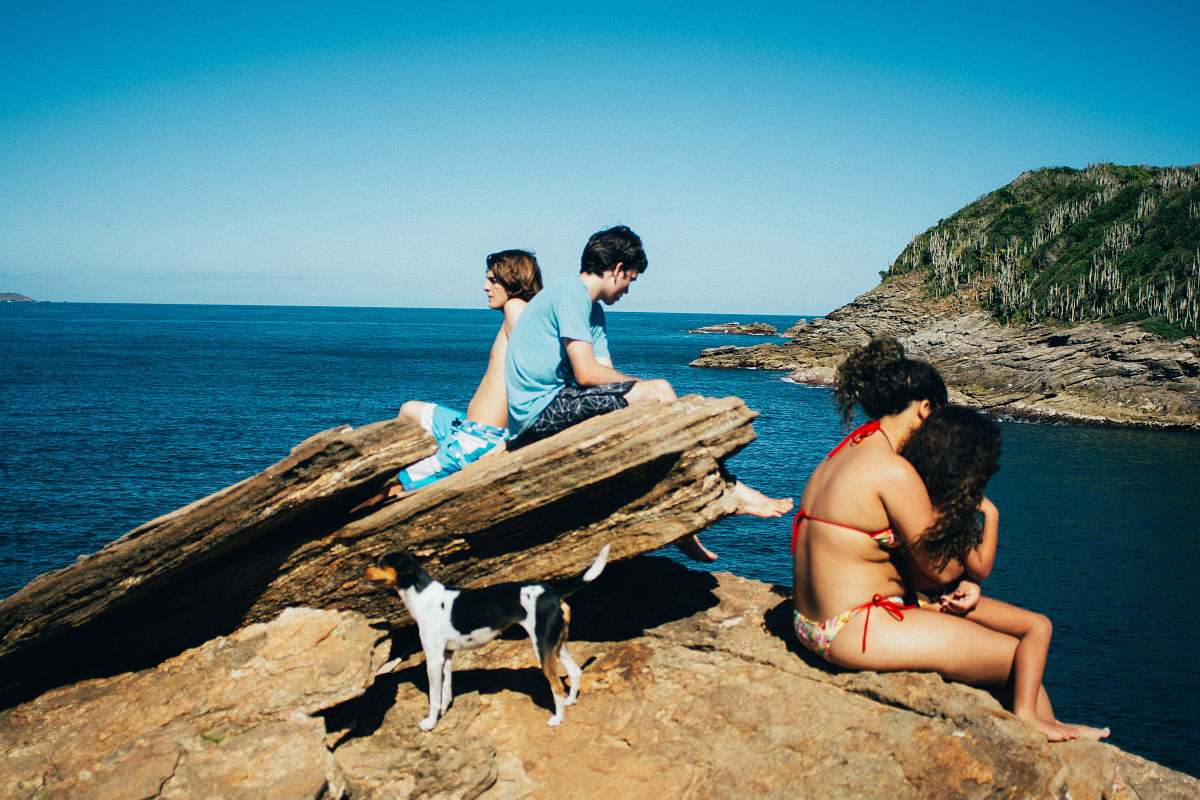 shoreline people sitting near ocean during daytime water