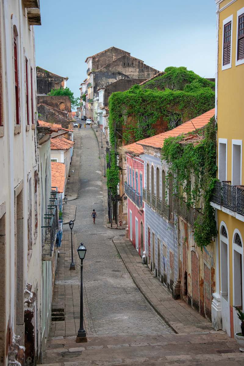 person person on road walking between buildings during daytime walkway