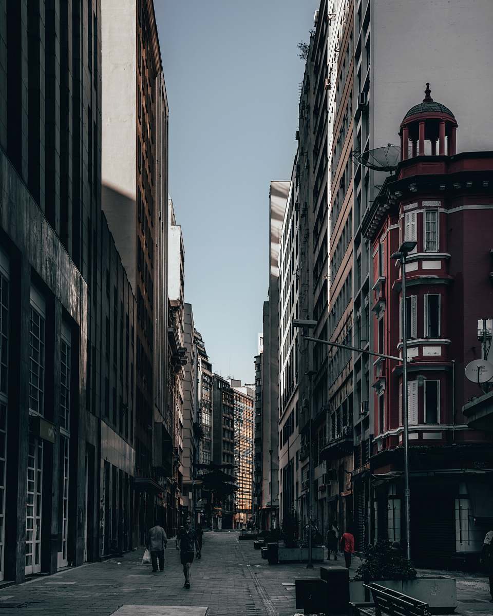 Experience the lively atmosphere of city life with this captivating image of individuals strolling between modern buildings. The scene captures the essence of urban exploration, highlighting the hustle and bustle of pedestrians navigating their way through a vibrant street. This versatile image is perfect for illustrating themes of community, daily life, and urban development, making it an ideal choice for blogs, websites, and marketing materials focused on city living.