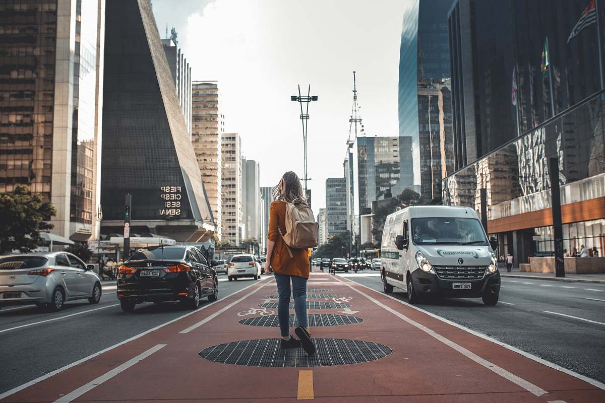 person photography of woman walking in between road with vehicles people