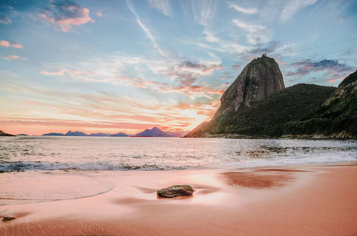 outdoors mountains near ocean under white clouds during daytime shoreline