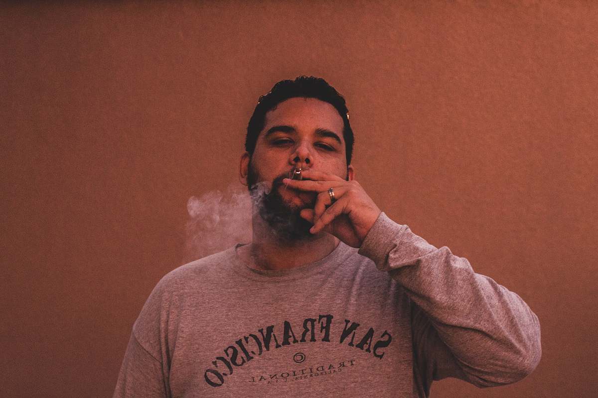 person man wearing gray San Francisco long-sleeved shirt while smoking human
