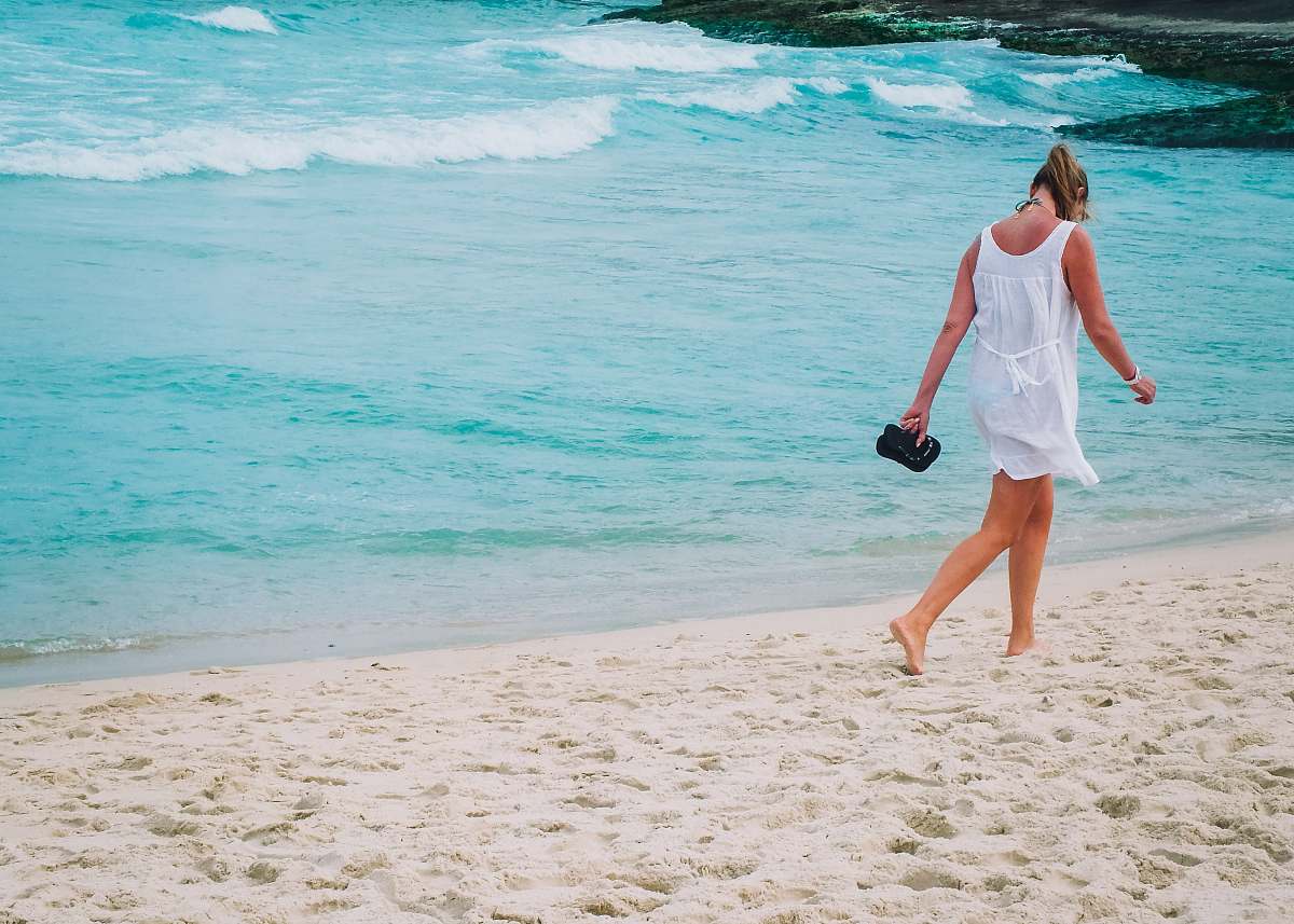 sea woman in white dress walks on white sand beach ocean