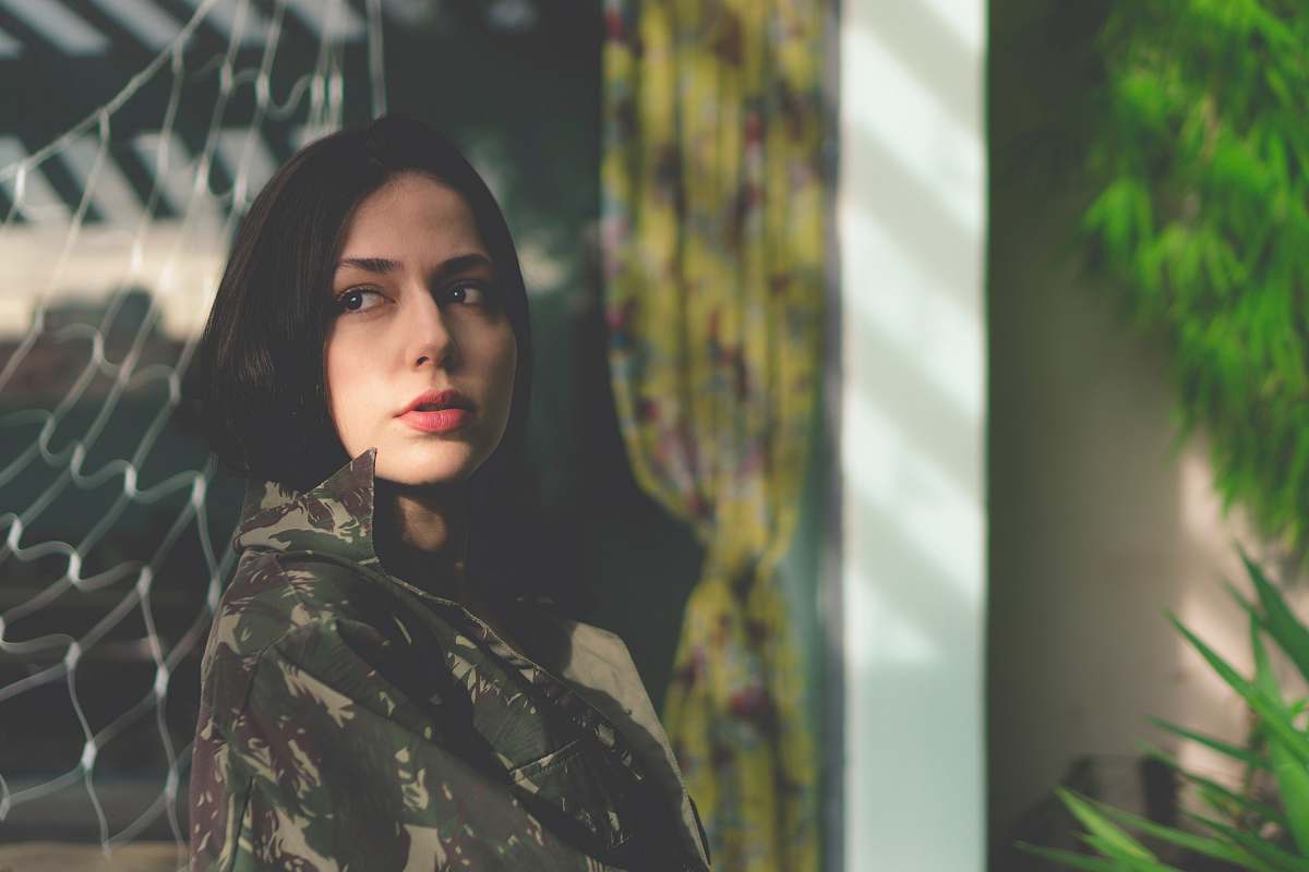 human woman in woodland camouflage top leaning on fence people