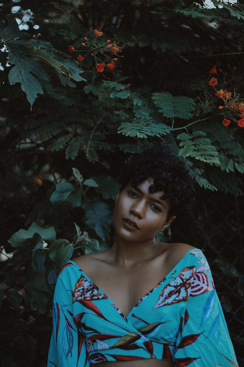 human woman wearing blue and red crop-top making post near plant people