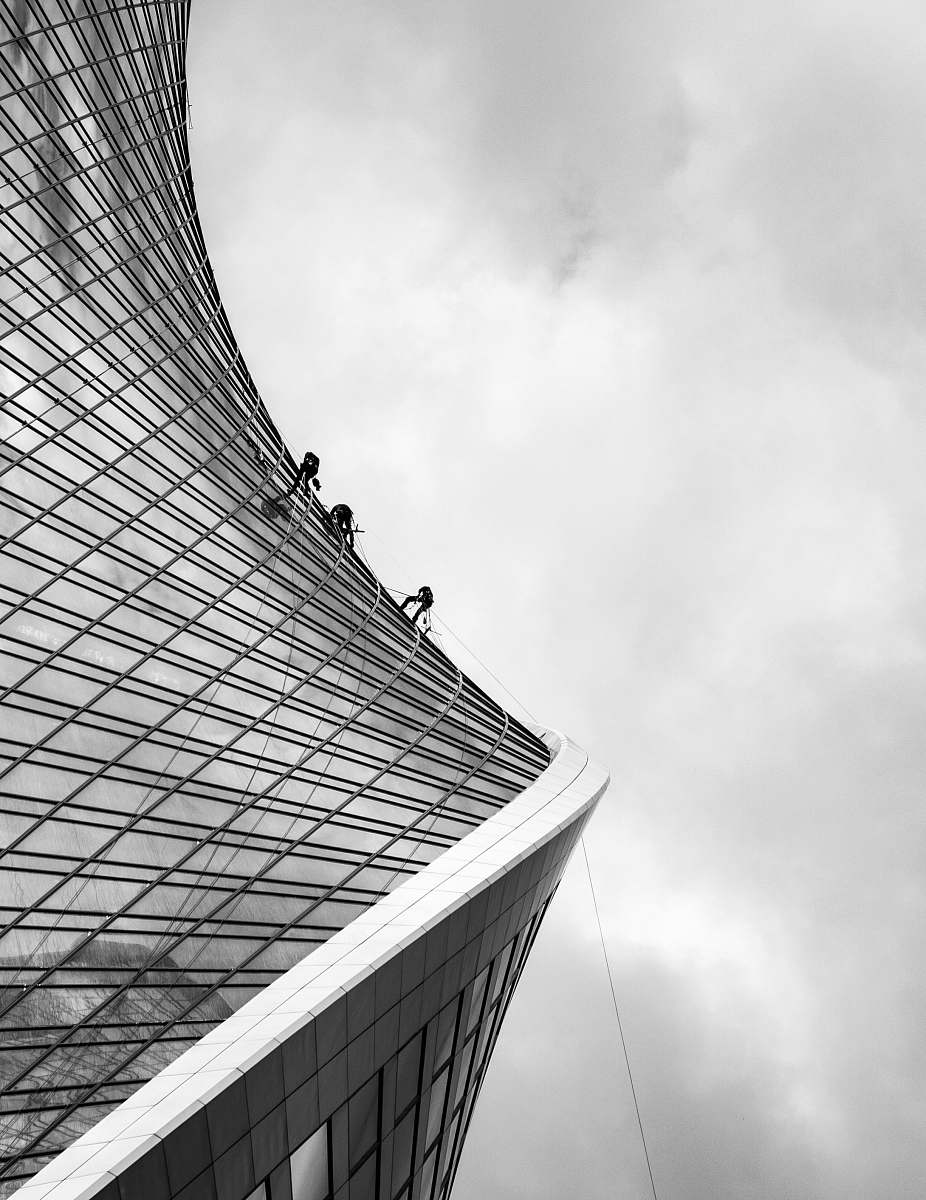 building grayscale photo of men climbing on building office building
