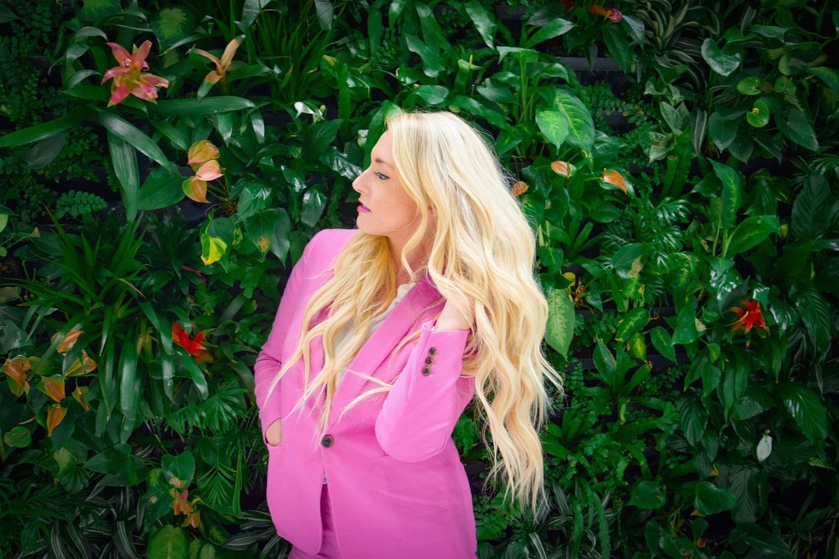 a woman in a pink dress standing in front of a green wall