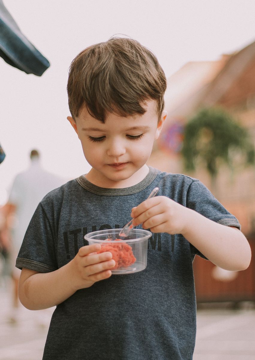 boy wearing gray crew-neck shirt holding up plastic cup