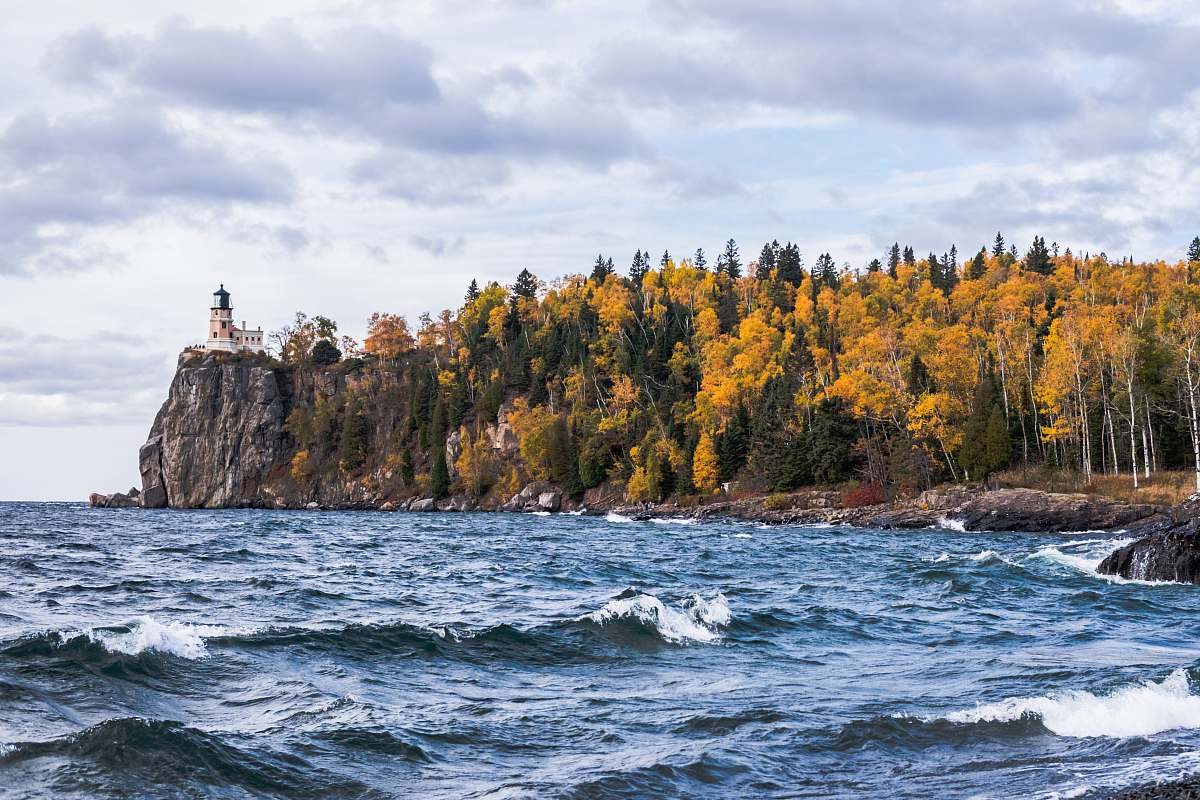 sea body of water near island with trees and lighthouse water