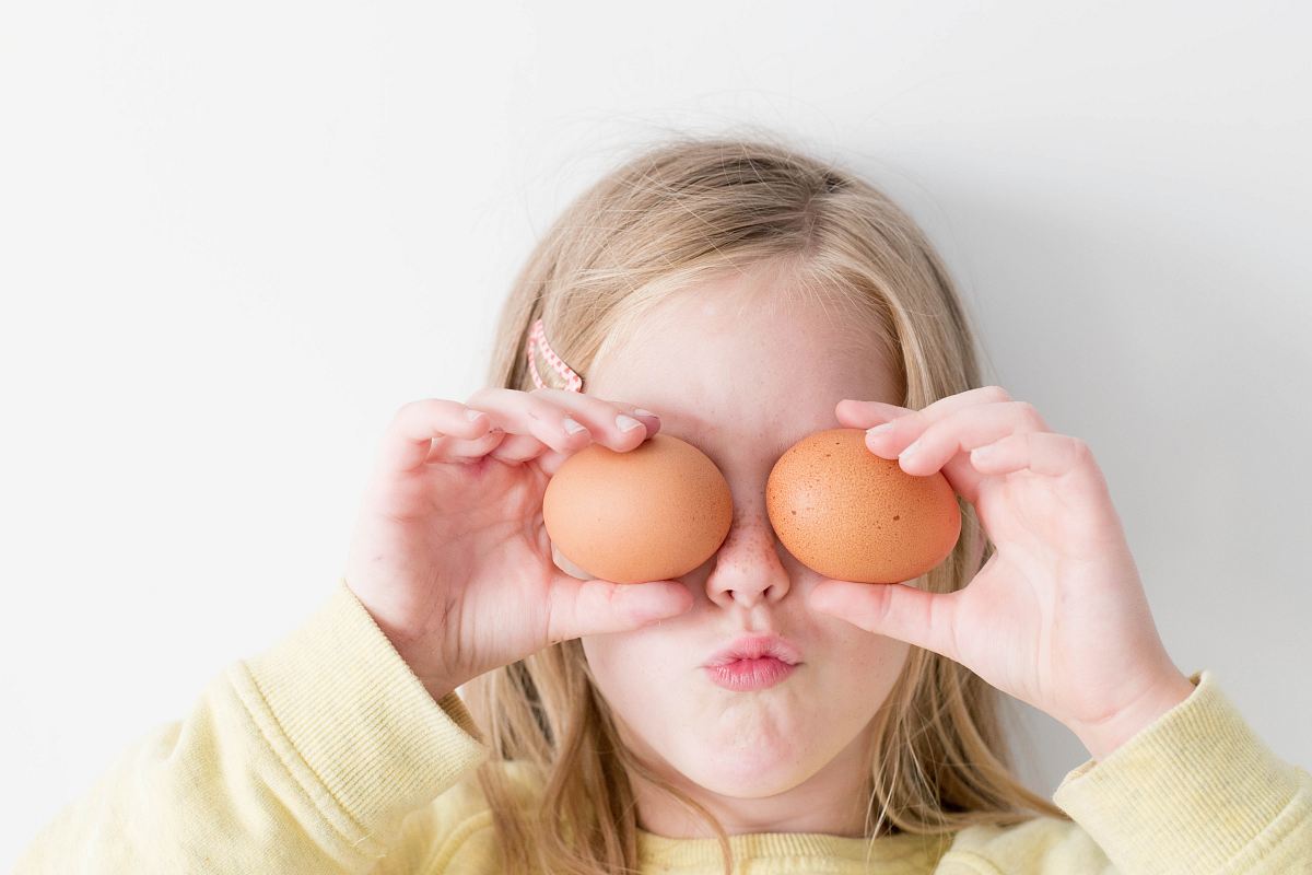 girl holding two eggs while putting it on her eyes
