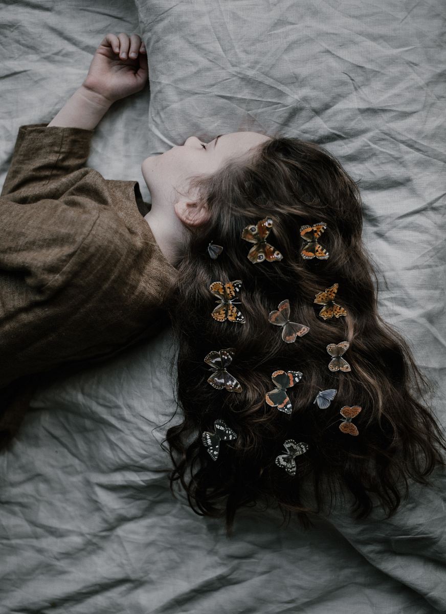 girl lying on gray bed sheet