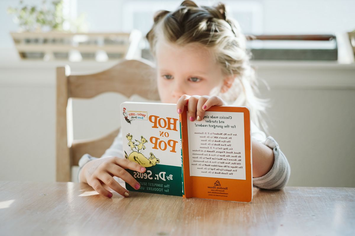 girl sitting while reading book