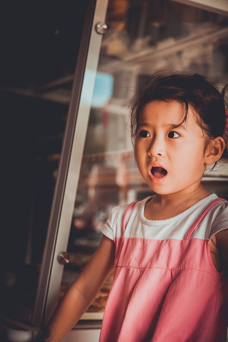 girl standing beside glass window