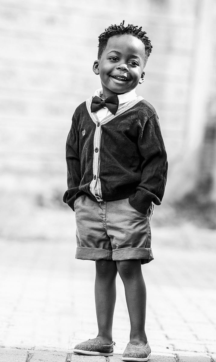 grayscale photo of boy in black button-up cardigan and shorts