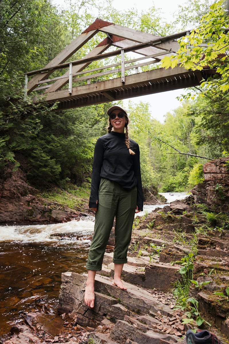 person woman in black jacket standing on brown wooden bridge outdoors