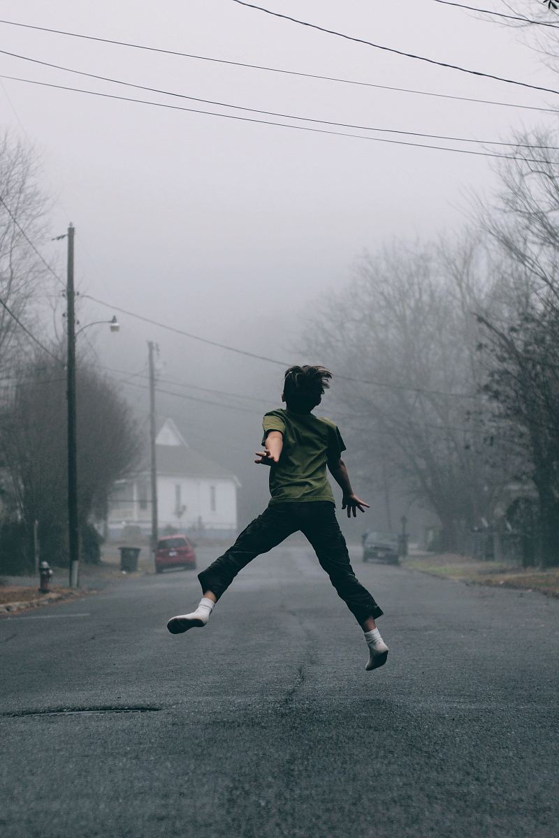 Kid jumps in the middle of the road on a foggy day