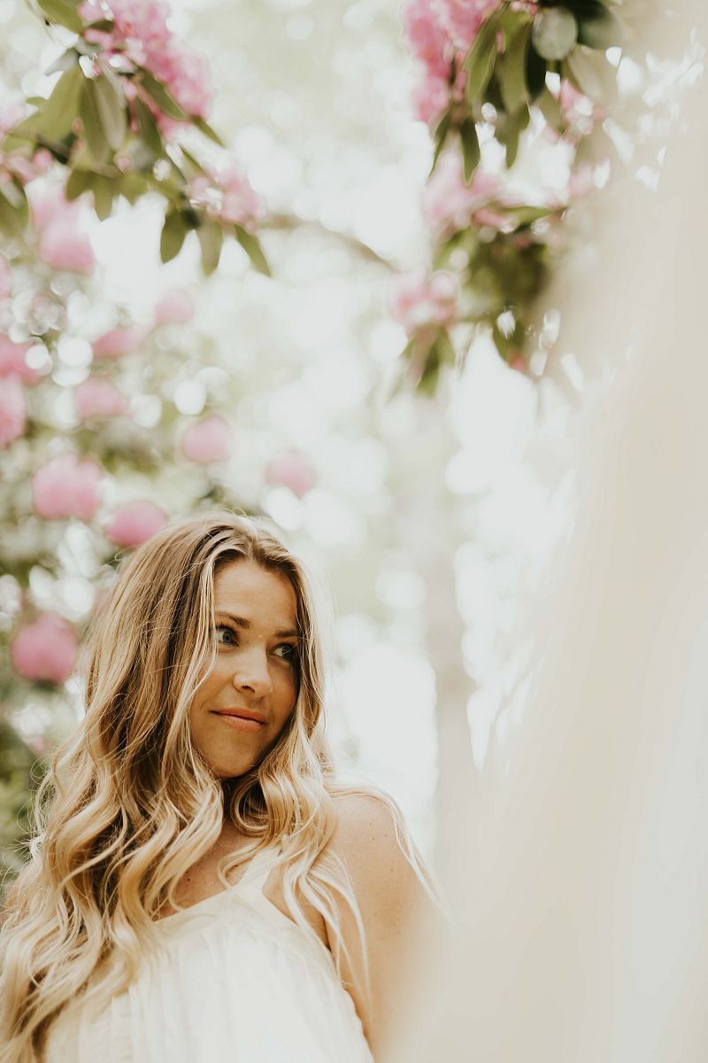 selective focus photography of woman surrounded with flowers