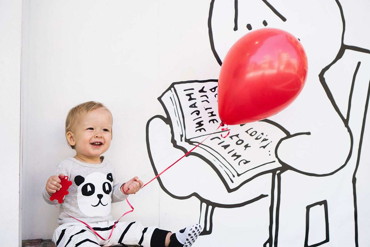 smiling toddler holding red balloon