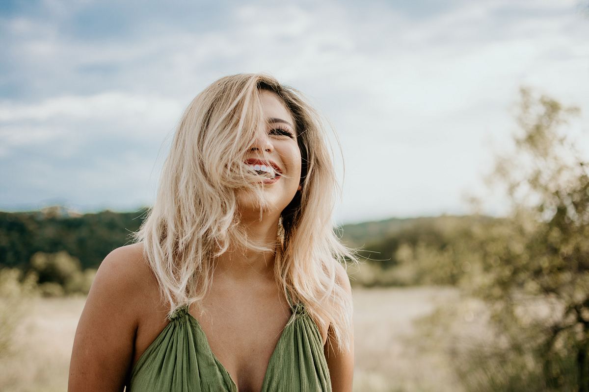 time-lapse photography of laughing woman with hair covering half of her face