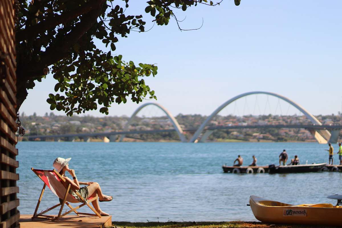 canoe person sitting on pool chair in front of sea with white suspension bridge rowboat