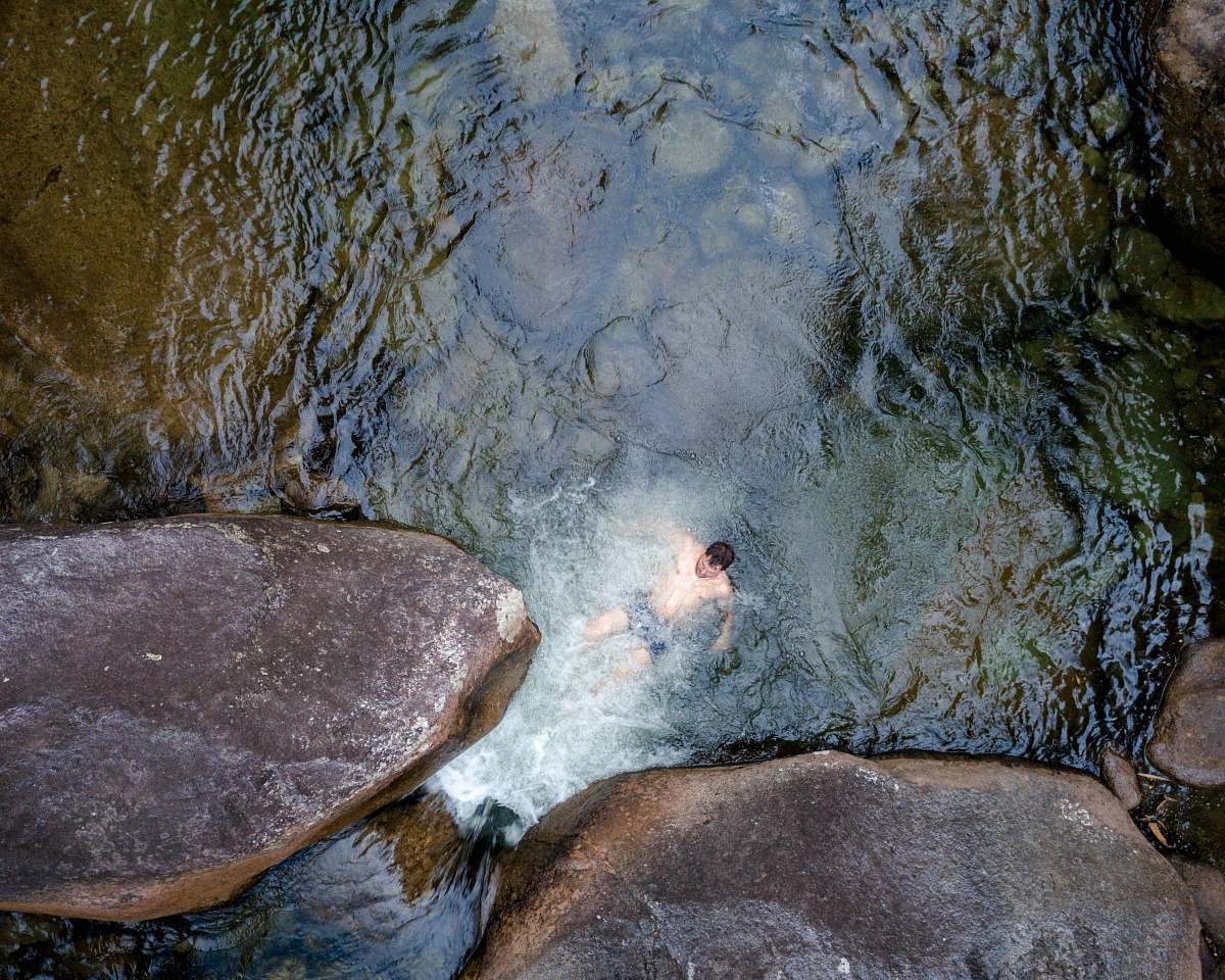 This captivating grey bird's eye view captures a serene moment of a man floating effortlessly on a rock in tranquil waters, while a playful group of turtles glides gracefully around him in the river. This image evokes a sense of relaxation and harmony with nature, making it perfect for use in travel blogs, wellness articles, or nature conservation campaigns. Whether illustrating a peaceful retreat or promoting eco-friendly lifestyles, this visual speaks to the heart of outdoor tranquility.