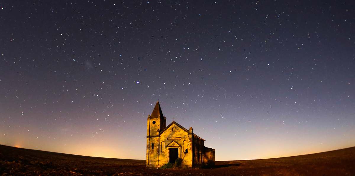 night worm's eye view photography of cathedral under gray skies filled of stars outdoors