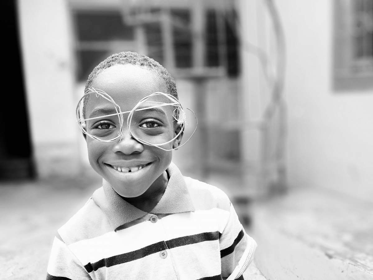 people grayscale photography of boy standing on ground front of house black-and-white