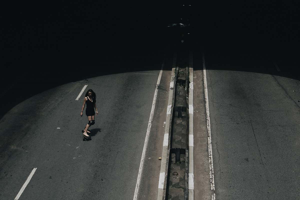 person high angle photo of woman riding on skateboard passing road grey