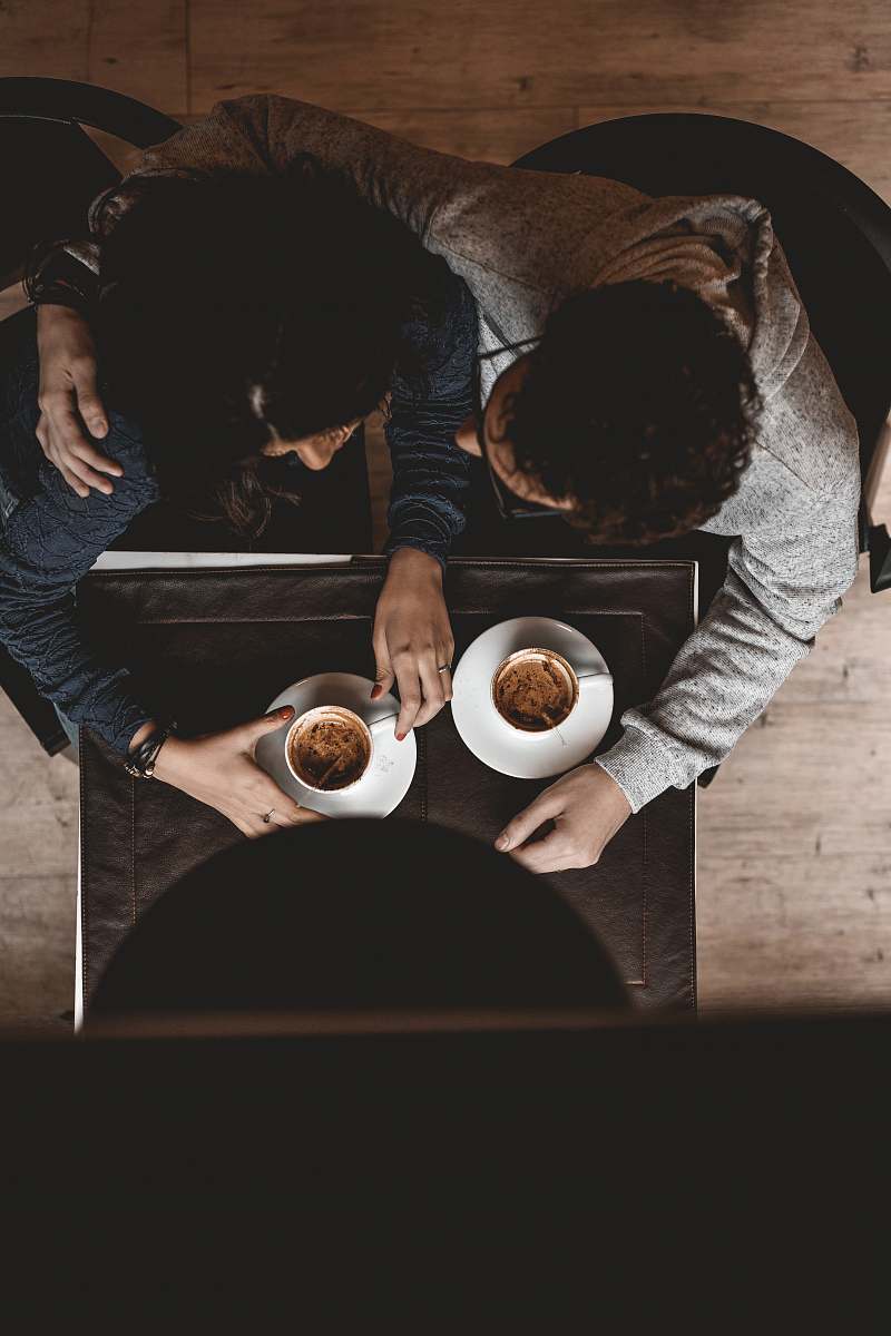 person man and woman sitting on floor while holding cups on table people