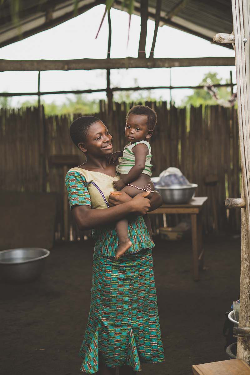 person smiling woman standing while holding baby togo