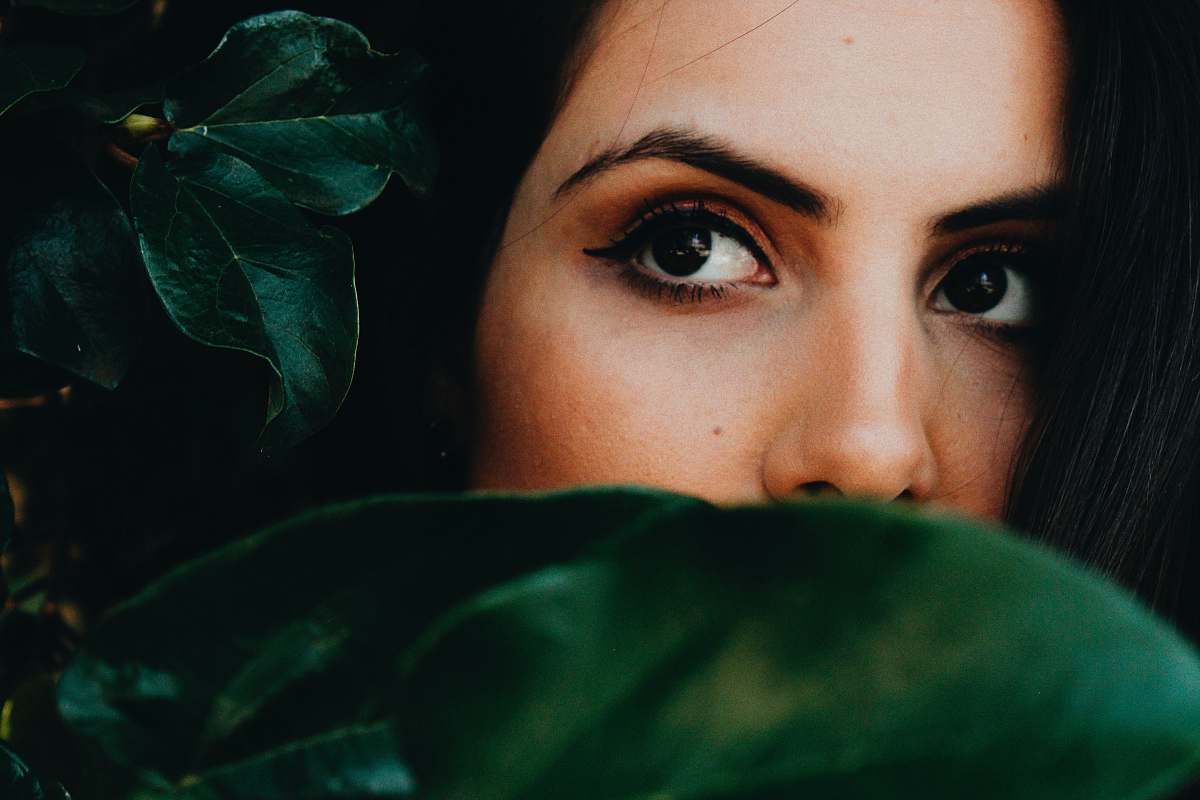 human half faced woman near green leaves person