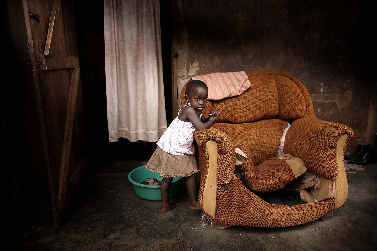 human girl standing near brown fabric sofa chair inside room people