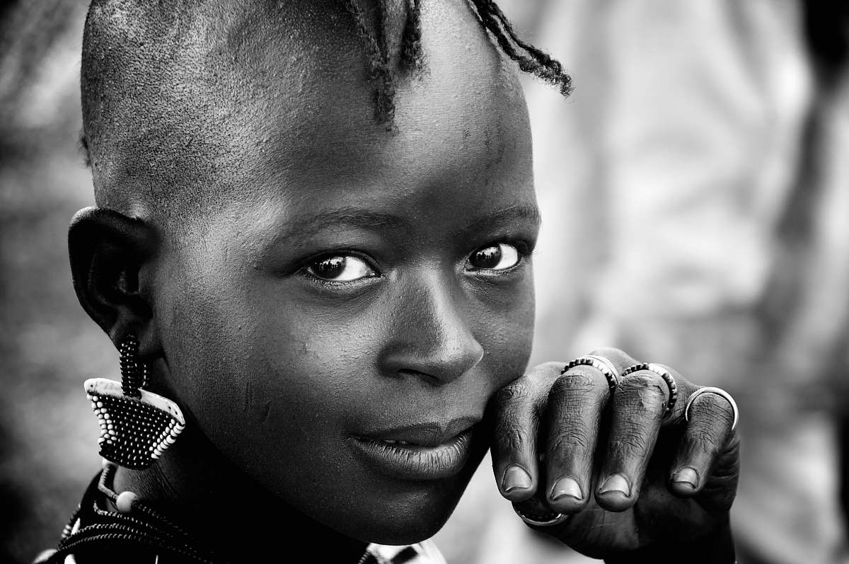 people toddler with earrings putting her hand on her face in selective focus greyscale portrait photography black-and-white