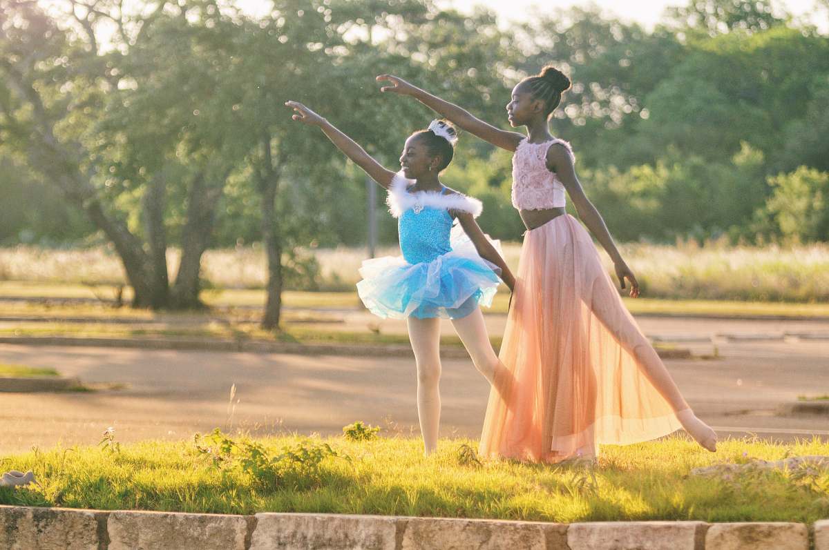 human two girls wearing blue and peach dresses dancing on green grass people