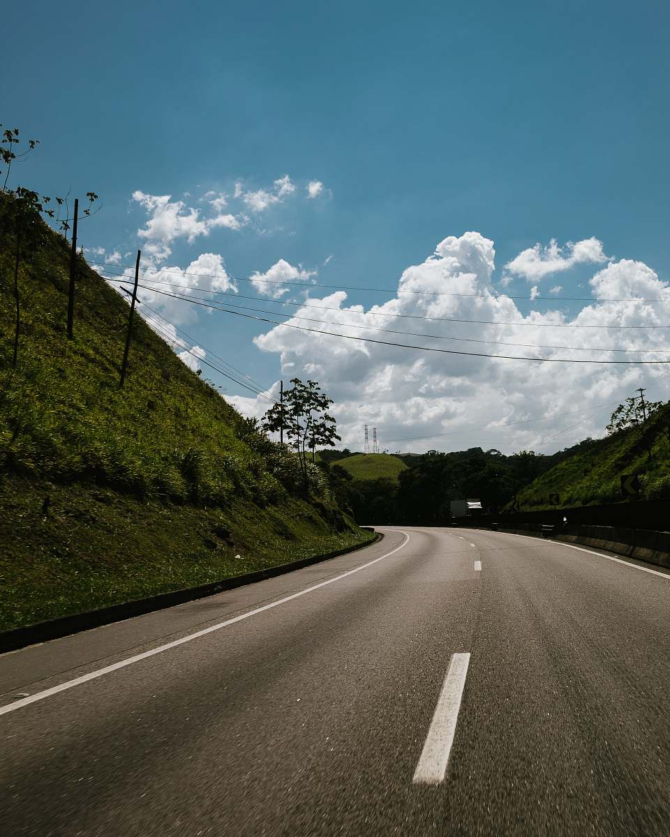 asphalt green hill near road during daytime tarmac