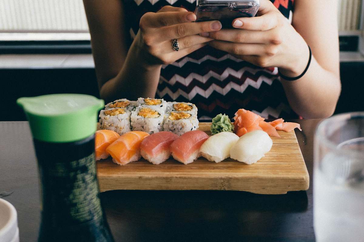 sushi person sitting in front of sushi dish on table human