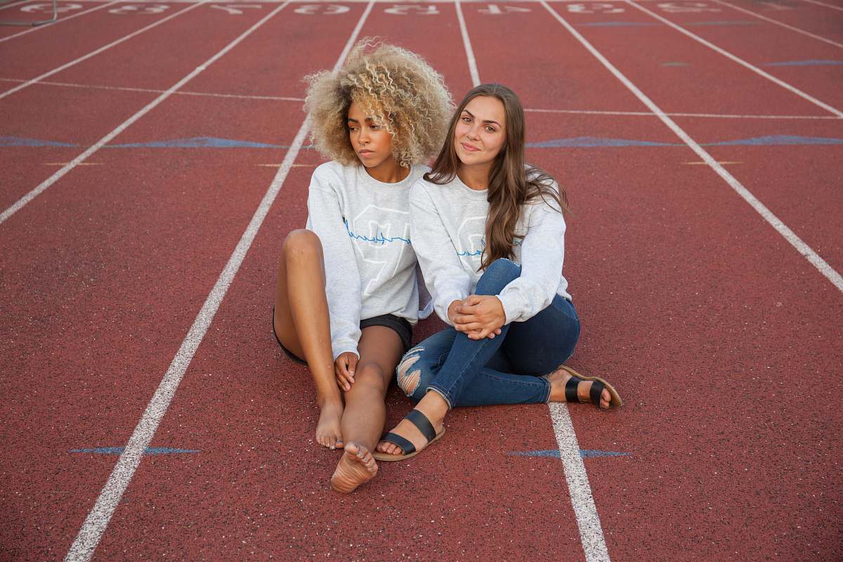 person photograph of two woman seating on track field people