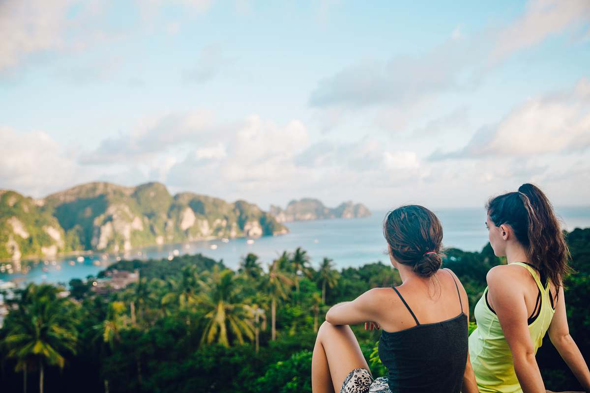 person two women sitting on hilltop people