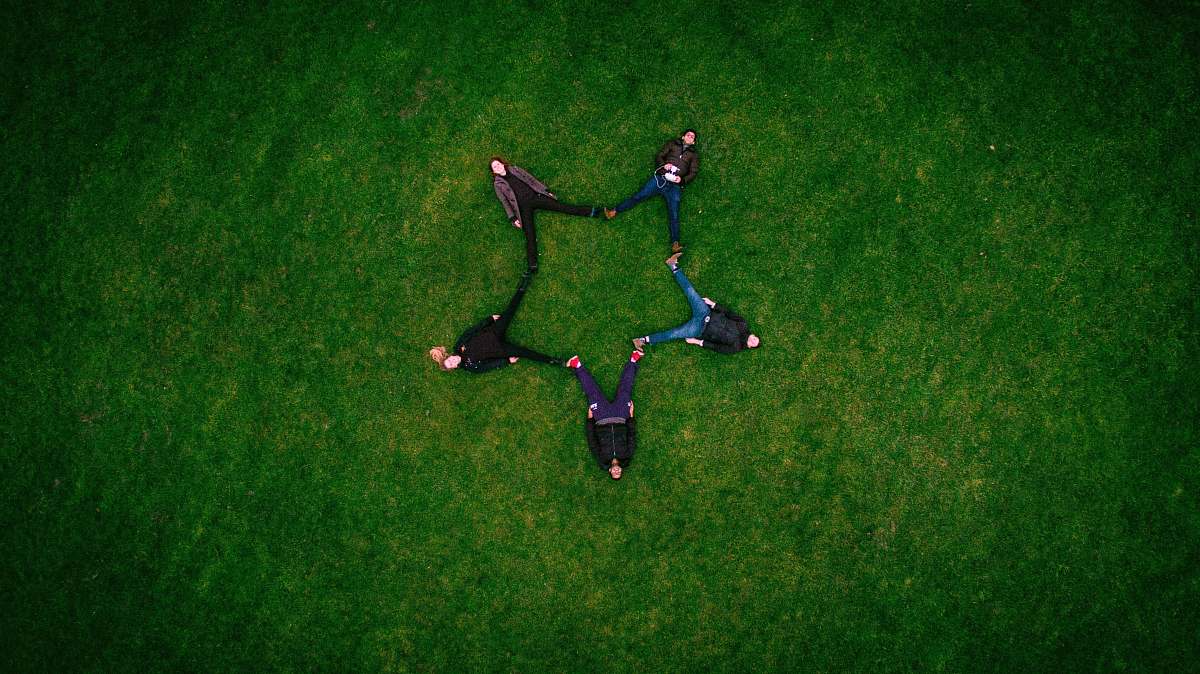 green five people laying on grass field making star sign field